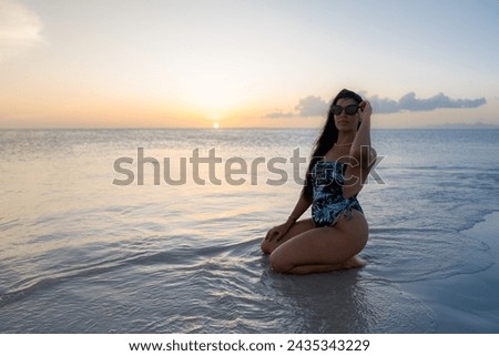 beautiful sunset on the sea horizon with latin woman sitting on the beach smiling and enjoying summer vacation