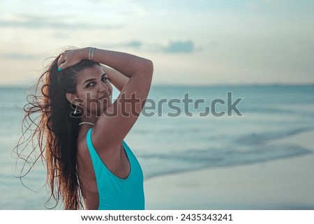 Beautiful face of brunette latin woman smiling on the beach holding her long hair
