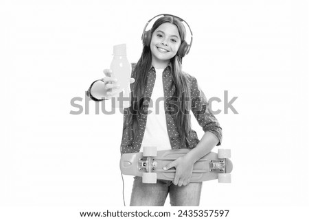 Teenagers lifestyle, casual youth culture. Teen girl with skateboard and headphones over white isolated studio background. Cool modern teenager in stylish clothes. Portrait of happy child girl.