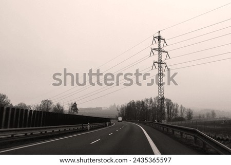 View from the car on the highway, in the background is a high - voltage, trees and misty sky, foggy weather, outdoor, black and white photography