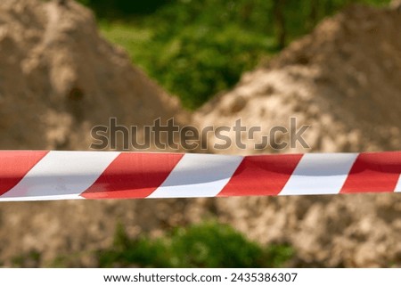Red and white fencing tape warning of danger during construction and repairs                              