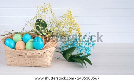 Banner. Easter eggs, feathers in a nest on a white wooden background. The minimal concept. Card with a copy of the place for the text.