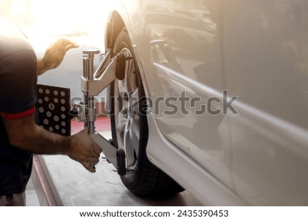 Vehicle wheel alignment. Tyre wheel alignment. Technician placing sensors to tires for Alignment.Electronic Wheel Balance. Royalty-Free Stock Photo #2435390453