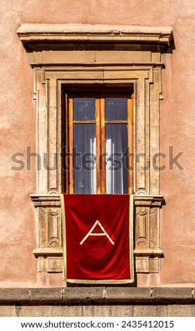 window with red banner or pennant with letter A for decotarion of old building facade for celebration of Saint Agata day in Catania