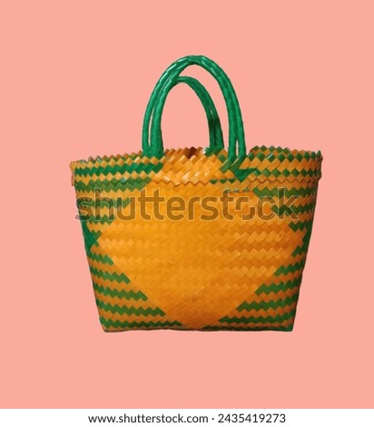 Weaving handmade basket made from plastic strands isolated on orange background. Royalty-Free Stock Photo #2435419273