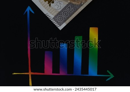 A paper banknote lies next to a colorful bar chart showing economic growth trends
