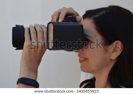 A woman photographer holds a camera in her hands and takes pictures. Close-up shot.