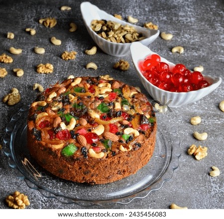 Savor the festive elegance in this Shutter Stock image featuring a Rich Plum Cake adorned with a medley of nuts and vibrant berries – a visual delight for indulgent occasions.