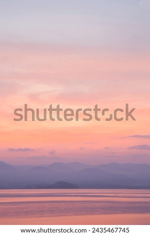 Vertical image Pastel sunset over tranquil lake and mountains.