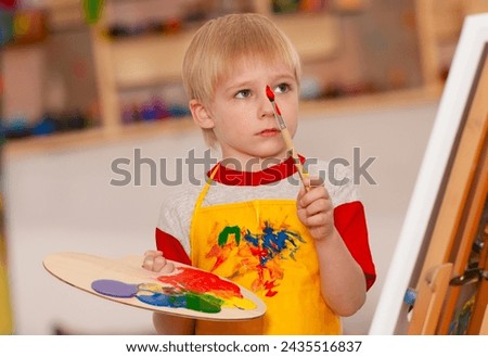 Little boy with easel in art school