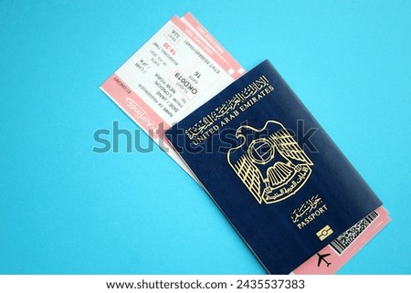 Blue United Arab Emirates passport with airline tickets on blue background close up. Tourism and travel concept Royalty-Free Stock Photo #2435537383