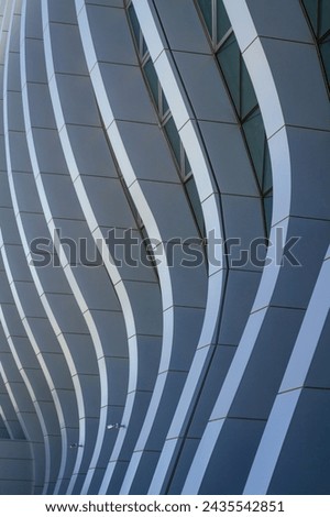 image is building with a very long, curved wall. wall is made metal and has very modern look to it. building appears to be large office building with many windows Royalty-Free Stock Photo #2435542851