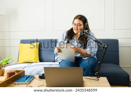 Latin woman recording an amateur podcast with a microphone and headphones in the living room