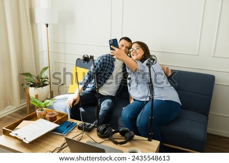 Hispanic woman taking a selfie with her happy guest after recording a podcast episode together 