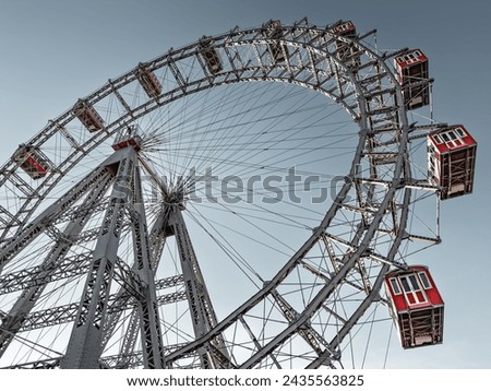 Wiener Riesenrad in Vienna, Austria. Historic tall Ferris wheel with red gondolas at the entrance of the Prater amusement park.  Royalty-Free Stock Photo #2435563825