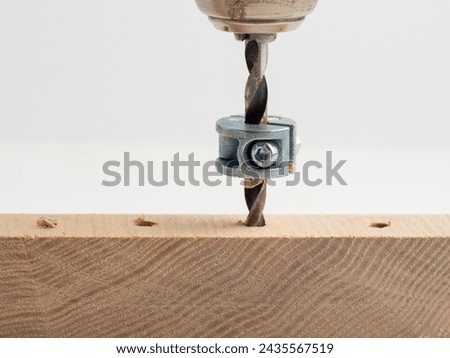 Electric drill  with depth collar on drill bit boring into a wooden board  isolated on a white background