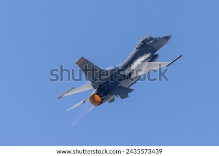 Close tail view of a F-16 Fighting Falcon in a high G maneuver, with condensation streaks at the wing roots and afterburner on  Royalty-Free Stock Photo #2435573439