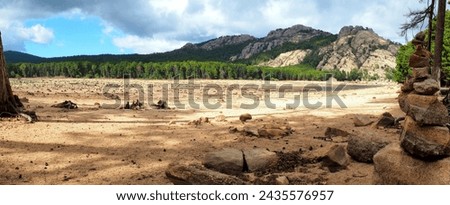 Near Porto-Vecchio, in the heart of Alta Rocca, Lake U Spidali is nestled between road and mountains. Due to the drought, the water level has dropped, revealing tree stumps cut before impoundment Royalty-Free Stock Photo #2435576957