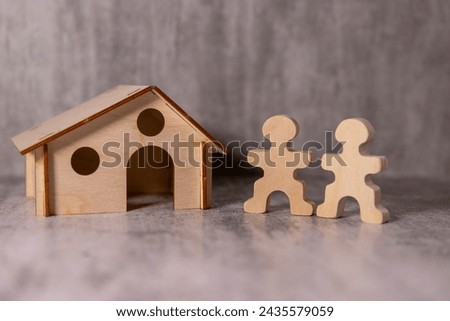 couple - man and woman wooden figure and wood house sign on red paper background