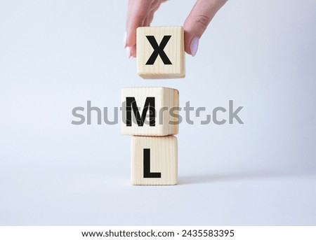 XML - Extensible Markup Language. Wooden cubes with word XML. Businessman hand. Beautiful white background. Business and Extensible Markup Language concept. Copy space.
