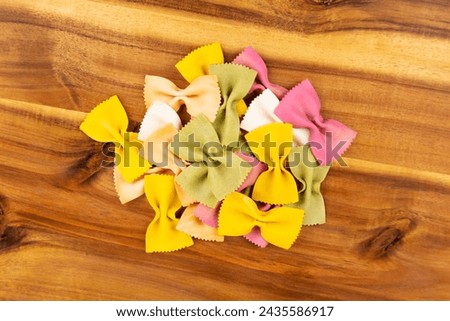 Pile of multicolored green yellow and red bowtie pasta on a wood cutting board