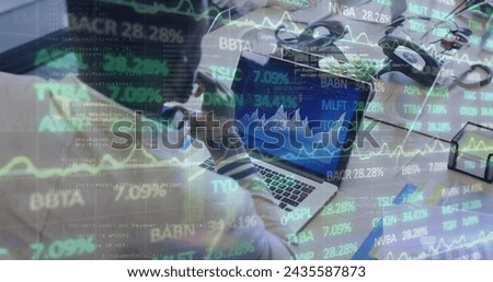 Image of financial data processing over businessman with face mask using laptop in office. global business and digital interface during covid 19 pandemic concept digitally generated image.
