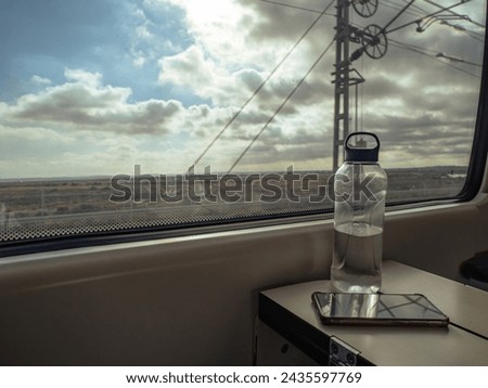 View from a Spanish Renfe train traveling at high speed in Andalusia, water bottle and smartphone