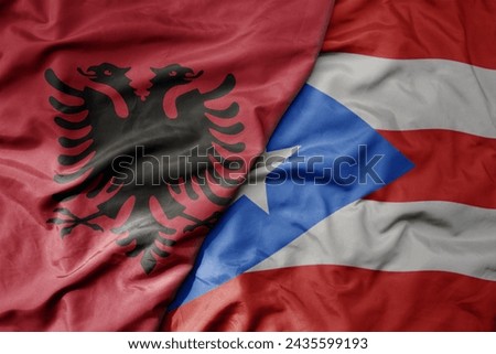 big waving national colorful flag of puerto rico and national flag of albania . macro