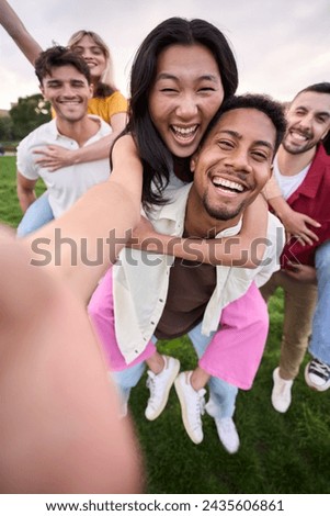 Vertical. Multirracial group of young friends taking selfie picture in piggyback in the park hugging by couples. Happy millennial people smiling together looking at camera outside. University students