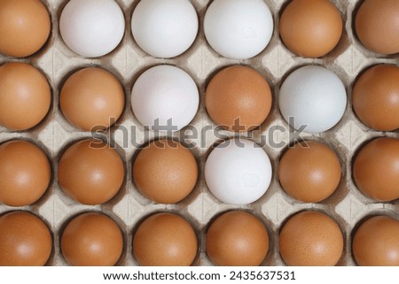 Chicken eggs in a cardboard box ready to cook on a yellow background