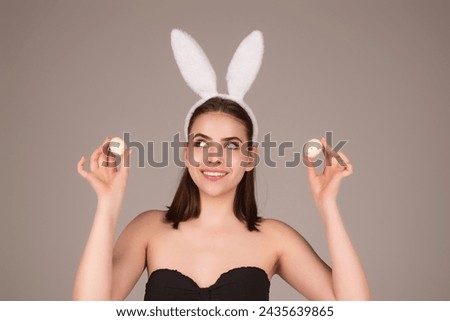 Close up photo of pretty girl wear easter fluffy bunny ears hold easter eggs, isolated studio background. Eater portrait of female bunny.