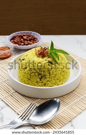 Nasi kuning (Indonesian for: "yellow rice"), or sometimes called nasi kunyit (Indonesian for: "turmeric rice"), is an Indonesian fragrant rice dish cooked with coconut milk and turmeric, hence the nam Royalty-Free Stock Photo #2435641855