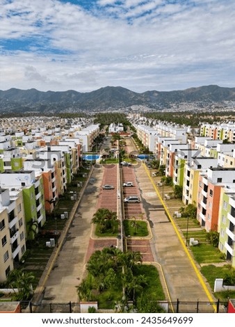 Vertical aerial shot capturing the colorful and orderly Real del Palmar neighborhood, surrounded by Acapulco's natural beauty