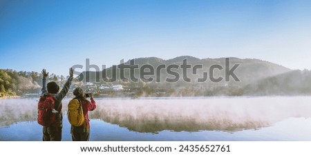 An Asian couple who is standing and watching the fog rising on the lake in the morning. Travel Ban Rak Thai village, Mae Hong Son in Thailand. Take a picture of the lake