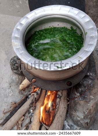 
In this picture, the fire is burning in the stove and the greens are being made in the pot.