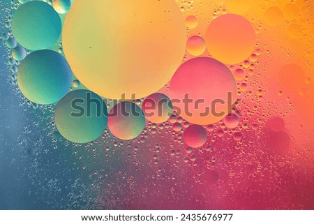 Abstract yellow, green, pink and blue colorful background with oil on water surface. Oil drops in water abstract psychedelic, abstract image. Royalty-Free Stock Photo #2435676977