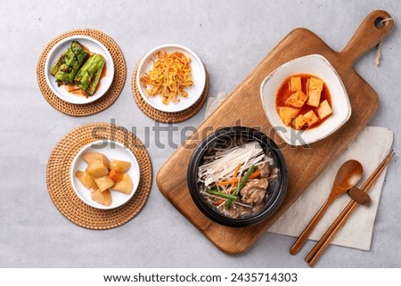 Korean food, budae jjigae, galbitang, earthen pot, bulgogi, pork belly, grilled, side dishes, kimchi, cucumbers, potatoes, vegetables Royalty-Free Stock Photo #2435714303