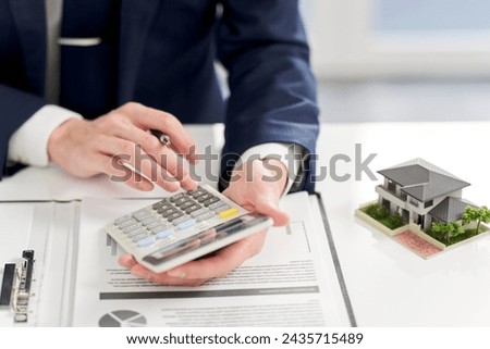 Businessman calculating money related to real estate Royalty-Free Stock Photo #2435715489