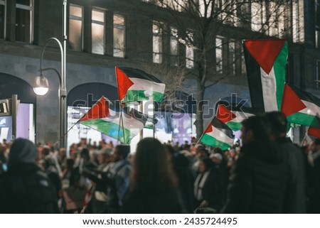 Pro - palestinian protests in Berlin. Flags of palestine waving between the people supporting palestine over israeli invasion of gaza.. Pro palestinian protests at night in european city