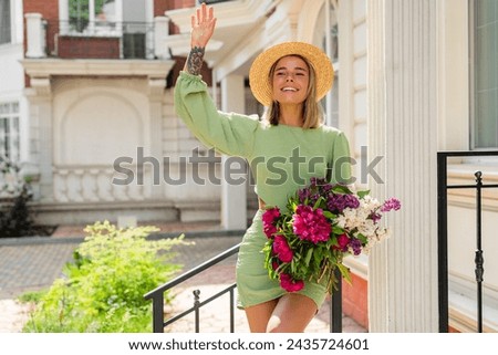 beautiful young woman in summer style outfit smiling happy walking with flowers in city street wearing straw hat fashion trend, peony garden