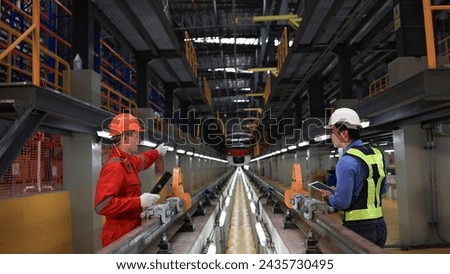 The railway chief engineer and maintenance engineer collaborate on maintaining the electric train tracks at the Sky train garage. Royalty-Free Stock Photo #2435730495