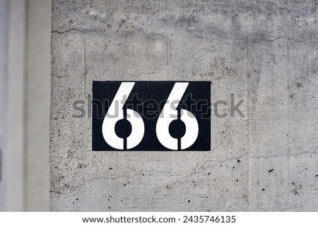 Close-up of white number 66 against black background on concrete wall at Swiss City of Zürich on a sunny winter morning. Photo taken March 9th, 2024, Zurich, Switzerland. Royalty-Free Stock Photo #2435746135
