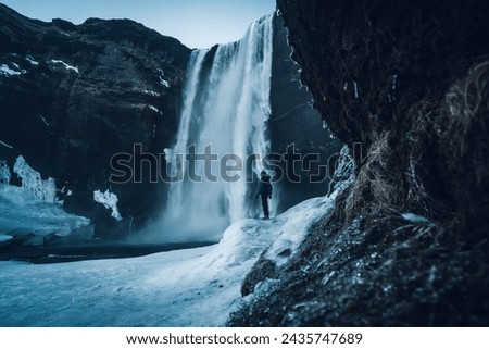 Silhouette of woman in winter in Iceland under Skogafoss waterfall