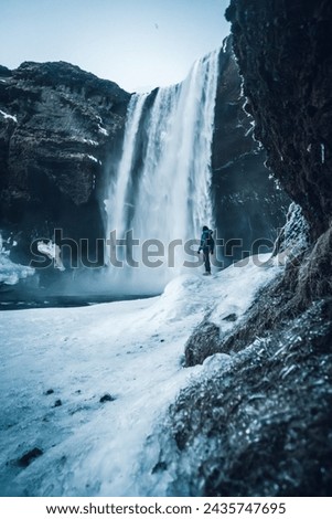 Silhouette of woman in winter in Iceland under the Skogafoss waterfall with temperatures of 20 below zero. With the ground frozen with ice