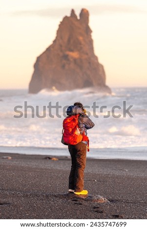Adventurous photographer woman from behind in winter in Iceland visiting the Reynisfjara Black Sand Beach