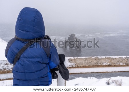 Adventurous woman in winter in Iceland looking at the frozen figure of Hvitserkur