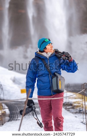 Photographer woman in winter in Iceland visiting Seljalandsfoss waterfall