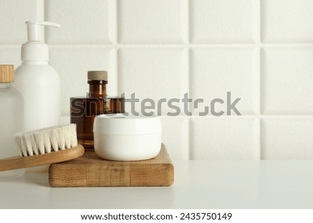 Bath accessories. Personal care products and wooden brush on white table near tiled wall, space for text