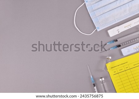 Virus antigen test, vaccine passport, medical face masks, vaccine vials with syringes on gray background with copy space