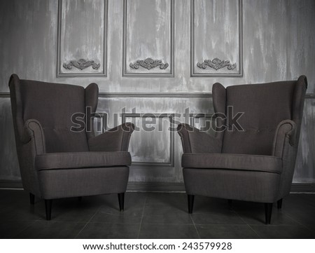 Two classic armchairs against a gray wall and floor. Copy space